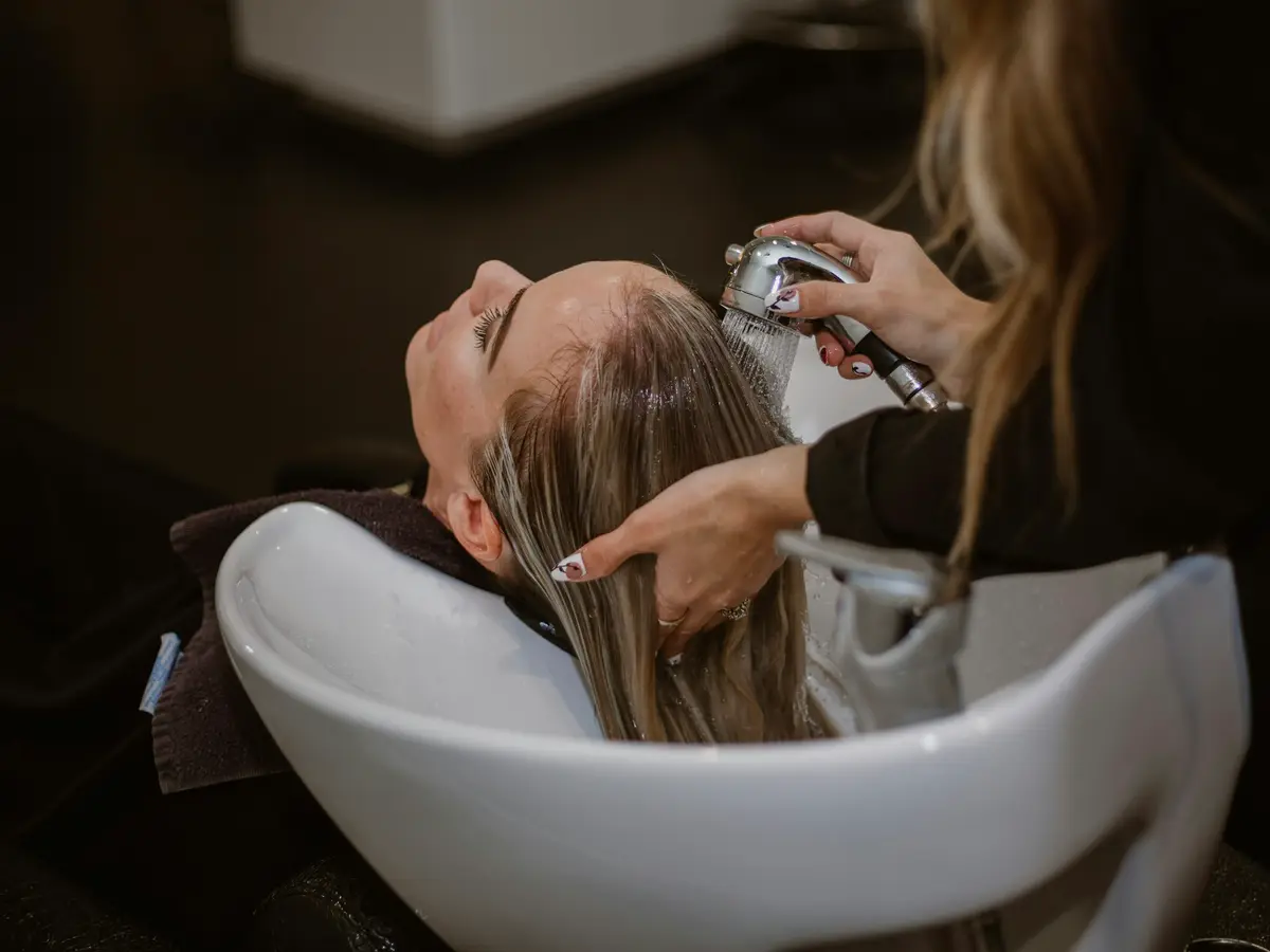 Profissional atendendo uma cliente no lavatório de um salão