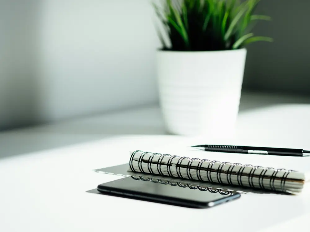 Caderno de anotações e celular sobre uma mesa